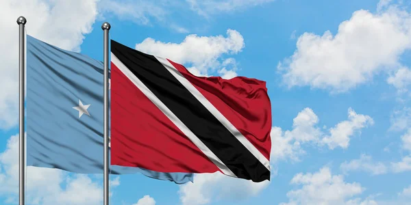 Mikronezya ve Trinidad ve Tobago bayrağı birlikte beyaz bulutlu mavi gökyüzüne karşı rüzgarda sallayarak. Diplomasi kavramı, uluslararası ilişkiler. — Stok fotoğraf