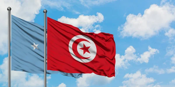 Mikronesien och Tunisien sjunker vifta i vinden mot vit grumlig blå himmel tillsammans. Diplomatisk koncept, internationella relationer. — Stockfoto