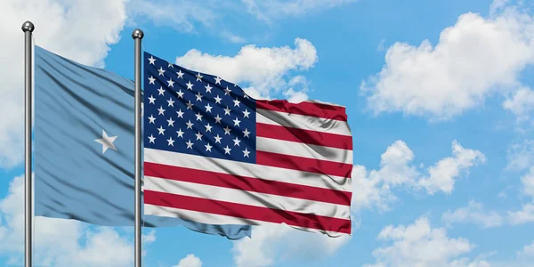 Micronésia e bandeira dos Estados Unidos agitando no vento contra o céu azul nublado branco juntos. Conceito de diplomacia, relações internacionais . — Fotografia de Stock