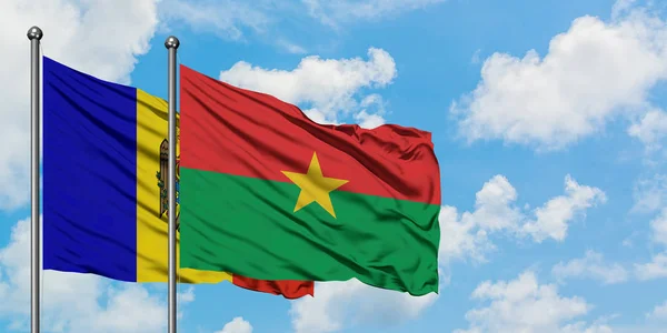 Bandera de Moldavia y Burkina Faso ondeando en el viento contra el cielo azul nublado blanco juntos. Concepto diplomático, relaciones internacionales . — Foto de Stock