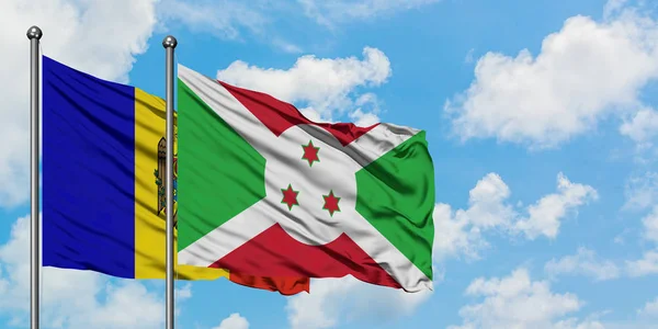 Bandera de Moldavia y Burundi ondeando en el viento contra el cielo azul nublado blanco juntos. Concepto diplomático, relaciones internacionales . — Foto de Stock