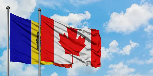 Bandera de Moldavia y Canadá ondeando en el viento contra el cielo azul nublado blanco juntos. Concepto diplomático, relaciones internacionales . — Foto de Stock