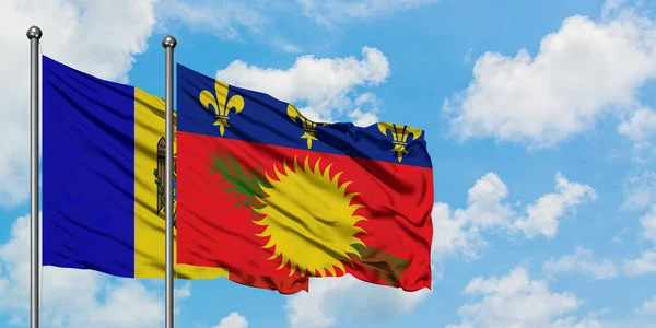 Bandera de Moldavia y Guadalupe ondeando en el viento contra el cielo azul nublado blanco juntos. Concepto diplomático, relaciones internacionales . — Foto de Stock
