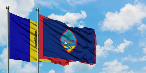 Bandera de Moldavia y Guam ondeando en el viento contra el cielo azul nublado blanco juntos. Concepto diplomático, relaciones internacionales . — Foto de Stock