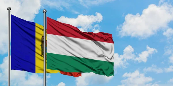 Bandera de Moldavia y Hungría ondeando en el viento contra el cielo azul nublado blanco juntos. Concepto diplomático, relaciones internacionales . — Foto de Stock