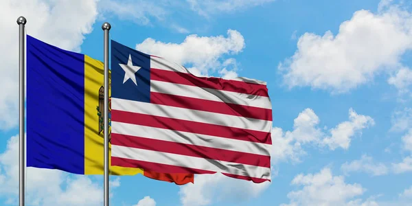 Bandera de Moldavia y Liberia ondeando en el viento contra el cielo azul nublado blanco juntos. Concepto diplomático, relaciones internacionales . — Foto de Stock