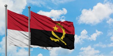 Monako ve Angola bayrağı birlikte beyaz bulutlu mavi gökyüzüne karşı rüzgarda sallayarak. Diplomasi kavramı, uluslararası ilişkiler.