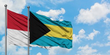 Monako ve Bahamalar bayrağı birlikte beyaz bulutlu mavi gökyüzüne karşı rüzgarda sallayarak. Diplomasi kavramı, uluslararası ilişkiler.