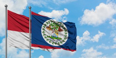 Monako ve Belize bayrağı birlikte beyaz bulutlu mavi gökyüzüne karşı rüzgarda sallayarak. Diplomasi kavramı, uluslararası ilişkiler.
