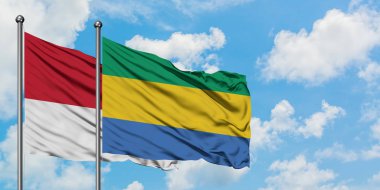 Monako ve Gabon bayrağı birlikte beyaz bulutlu mavi gökyüzüne karşı rüzgarda sallayarak. Diplomasi kavramı, uluslararası ilişkiler.
