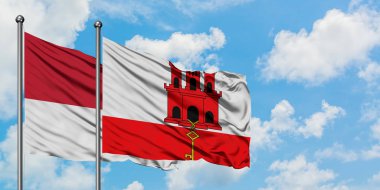 Monako ve Cebelitarık bayrağı birlikte beyaz bulutlu mavi gökyüzüne karşı rüzgarda sallayarak. Diplomasi kavramı, uluslararası ilişkiler.