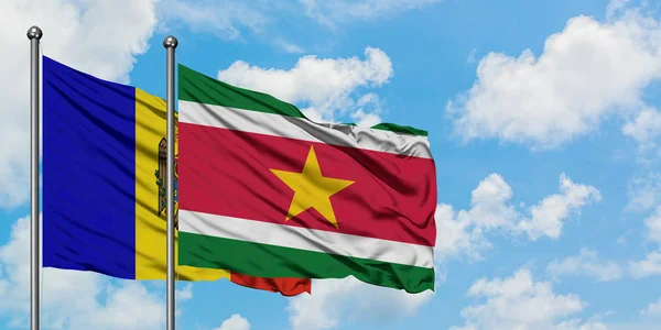 Bandera de Moldavia y Surinam ondeando en el viento contra el cielo azul nublado blanco juntos. Concepto diplomático, relaciones internacionales . — Foto de Stock