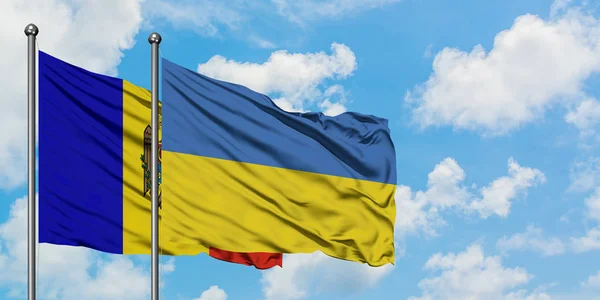 Moldavsko a Ukrajina mávaly ve větru proti bíle zatažené modré obloze. Diplomacie, mezinárodní vztahy. — Stock fotografie