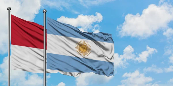 Bandera de Mónaco y Argentina ondeando en el viento contra el cielo azul nublado blanco juntos. Concepto diplomático, relaciones internacionales . — Foto de Stock