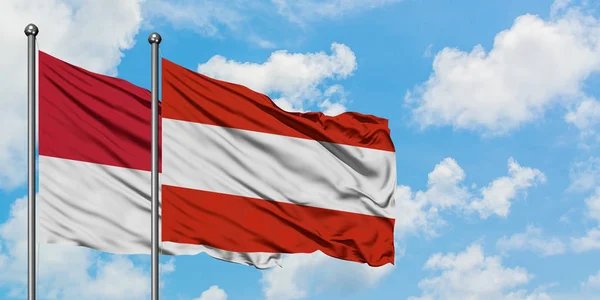 一緒に白い曇り青い空に対して風に手を振るモナコとオーストリアの旗。外交概念、国際関係. — ストック写真