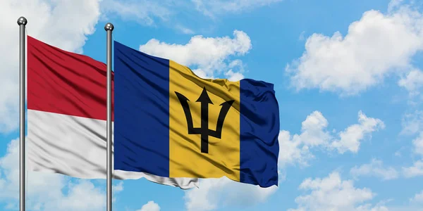 Bandera de Mónaco y Barbados ondeando en el viento contra el cielo azul nublado blanco juntos. Concepto diplomático, relaciones internacionales . — Foto de Stock