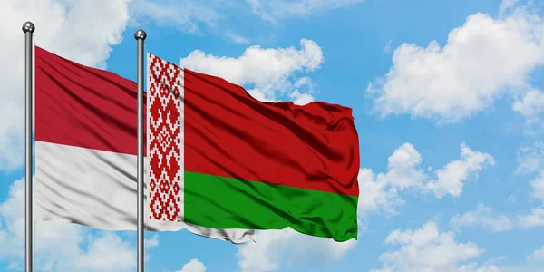 Mônaco e a bandeira da Bielorrússia agitando no vento contra o céu azul nublado branco juntos. Conceito de diplomacia, relações internacionais . — Fotografia de Stock