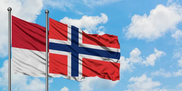 Bandera de Mónaco y Bouvet Islands ondeando en el viento contra el cielo azul nublado blanco juntos. Concepto diplomático, relaciones internacionales . — Foto de Stock
