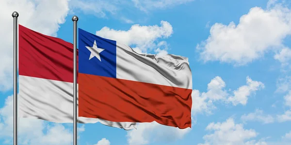 Bandera de Mónaco y Chile ondeando en el viento contra el cielo azul nublado blanco juntos. Concepto diplomático, relaciones internacionales . — Foto de Stock