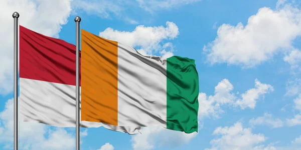 Monaco and Cote D'Ivoire flag waving in the wind against white cloudy blue sky together. Diplomacy concept, international relations. — Stock Photo, Image