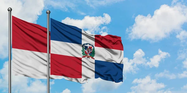 一緒に白い曇り青い空に対して風に手を振るモナコとドミニカ共和国の旗。外交概念、国際関係. — ストック写真