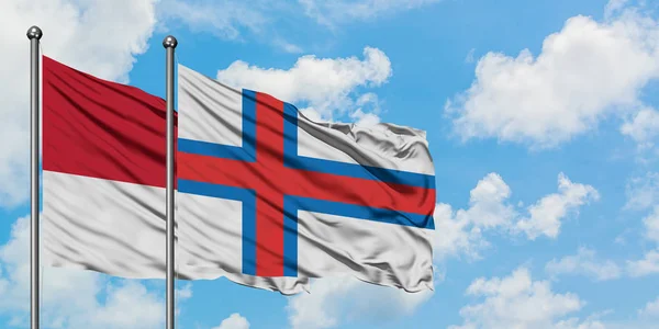 Monacké a Faerské ostrovy vlaje ve větru proti bíle zatažené modré obloze. Diplomacie, mezinárodní vztahy. — Stock fotografie