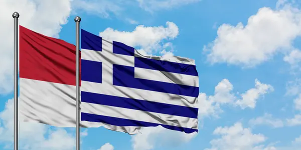 Mônaco e a bandeira da Grécia agitando no vento contra o céu azul nublado branco juntos. Conceito de diplomacia, relações internacionais . — Fotografia de Stock