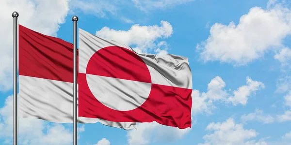 Bandera de Mónaco y Groenlandia ondeando en el viento contra el cielo azul nublado blanco juntos. Concepto diplomático, relaciones internacionales . — Foto de Stock