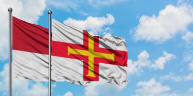 Monako ve Guernsey bayrağı birlikte beyaz bulutlu mavi gökyüzüne karşı rüzgarda sallayarak. Diplomasi kavramı, uluslararası ilişkiler.