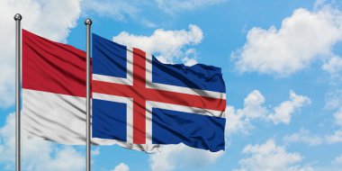 Monako ve İzlanda bayrağı birlikte beyaz bulutlu mavi gökyüzüne karşı rüzgarda sallayarak. Diplomasi kavramı, uluslararası ilişkiler.