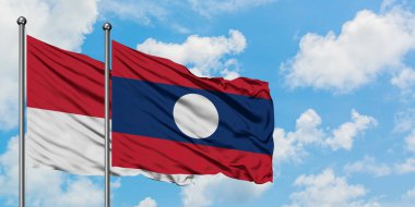 Monako ve Laos bayrağı birlikte beyaz bulutlu mavi gökyüzüne karşı rüzgarda sallayarak. Diplomasi kavramı, uluslararası ilişkiler.