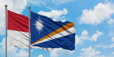 Monako ve Marshall Adaları bayrağı birlikte beyaz bulutlu mavi gökyüzüne karşı rüzgarda sallayarak. Diplomasi kavramı, uluslararası ilişkiler.