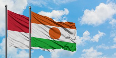 Monako ve Nijer bayrağı birlikte beyaz bulutlu mavi gökyüzüne karşı rüzgarda sallayarak. Diplomasi kavramı, uluslararası ilişkiler.