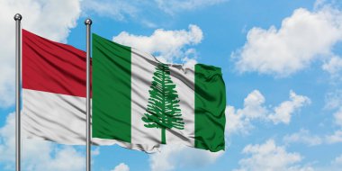 Monako ve Norfolk Adası bayrağı birlikte beyaz bulutlu mavi gökyüzüne karşı rüzgarda sallayarak. Diplomasi kavramı, uluslararası ilişkiler.