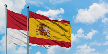 Monako ve İspanya bayrağı birlikte beyaz bulutlu mavi gökyüzüne karşı rüzgarsal sallayarak. Diplomasi kavramı, uluslararası ilişkiler.