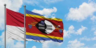 Monako ve Svaziland bayrağı birlikte beyaz bulutlu mavi gökyüzüne karşı rüzgarda sallayarak. Diplomasi kavramı, uluslararası ilişkiler.