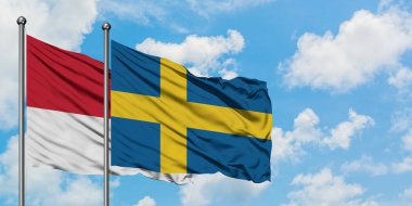 Monako ve İsveç bayrağı birlikte beyaz bulutlu mavi gökyüzüne karşı rüzgarsal sallayarak. Diplomasi kavramı, uluslararası ilişkiler.