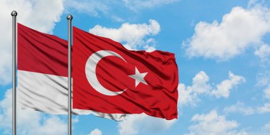 Monako ve Türkiye bayrağı havada sallanan beyaz bulutlu mavi gökyüzüne karşı birlikte. Diplomasi kavramı, uluslararası ilişkiler.