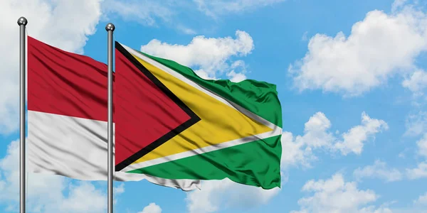 Bandera de Mónaco y Guyana ondeando en el viento contra el cielo azul nublado blanco juntos. Concepto diplomático, relaciones internacionales . —  Fotos de Stock