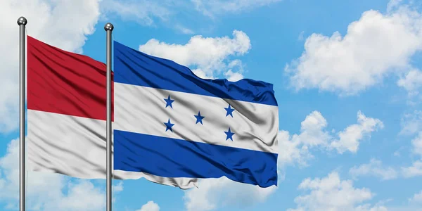 Монако і Гондурас прапор розмахував вітром проти білого хмарного синього неба разом. Концепція дипломатії, міжнародні відносини. — стокове фото