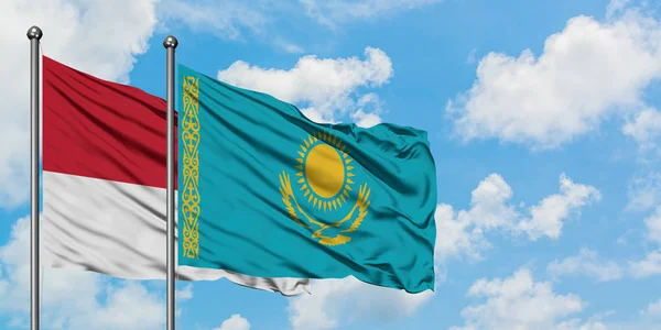 Bandera de Mónaco y Kazajstán ondeando en el viento contra el cielo azul nublado blanco juntos. Concepto diplomático, relaciones internacionales . — Foto de Stock