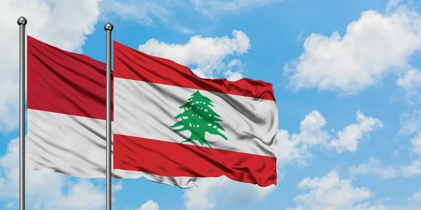 Bandera de Mónaco y Líbano ondeando en el viento contra el cielo azul nublado blanco juntos. Concepto diplomático, relaciones internacionales . — Foto de Stock