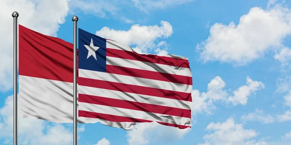 Monako ve Liberya bayrağı birlikte beyaz bulutlu mavi gökyüzüne karşı rüzgarda sallayarak. Diplomasi kavramı, uluslararası ilişkiler. — Stok fotoğraf