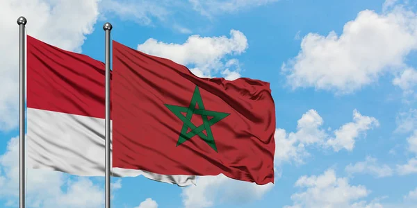 Bandera de Mónaco y Marruecos ondeando en el viento contra el cielo azul nublado blanco juntos. Concepto diplomático, relaciones internacionales . — Foto de Stock