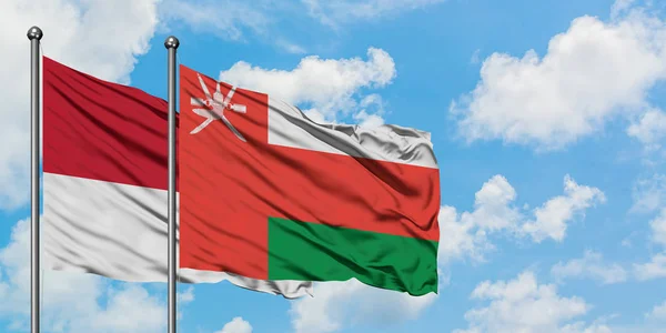 Bandera de Mónaco y Omán ondeando en el viento contra el cielo azul nublado blanco juntos. Concepto diplomático, relaciones internacionales . — Foto de Stock