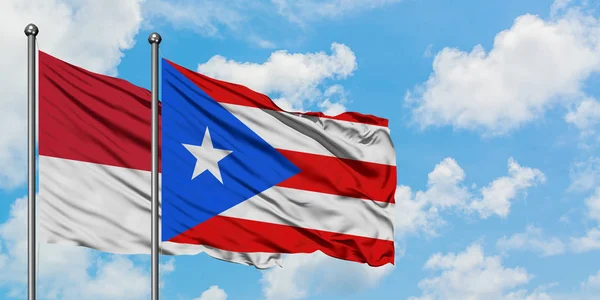 Monako ve Porto Riko bayrağı birlikte beyaz bulutlu mavi gökyüzüne karşı rüzgarda sallayarak. Diplomasi kavramı, uluslararası ilişkiler. — Stok fotoğraf