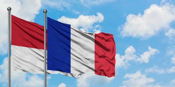 Monako i Reunion flaga machając w wiatr przed białym zachmurzone błękitne niebo razem. Koncepcja dyplomacji, stosunki międzynarodowe. — Zdjęcie stockowe