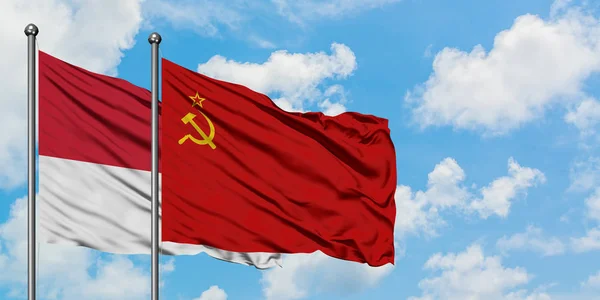 Monaco e la bandiera dell'Unione Sovietica sventolano nel vento contro il bianco cielo blu nuvoloso insieme. Concetto di diplomazia, relazioni internazionali . — Foto Stock