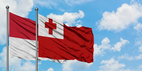 Bandera de Mónaco y Tonga ondeando en el viento contra el cielo azul nublado blanco juntos. Concepto diplomático, relaciones internacionales . — Foto de Stock