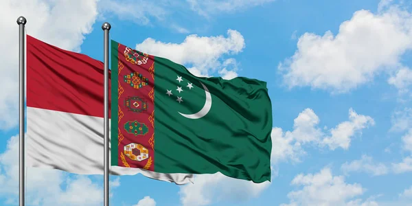 Bandera de Mónaco y Turkmenistán ondeando en el viento contra el cielo azul nublado blanco juntos. Concepto diplomático, relaciones internacionales . — Foto de Stock